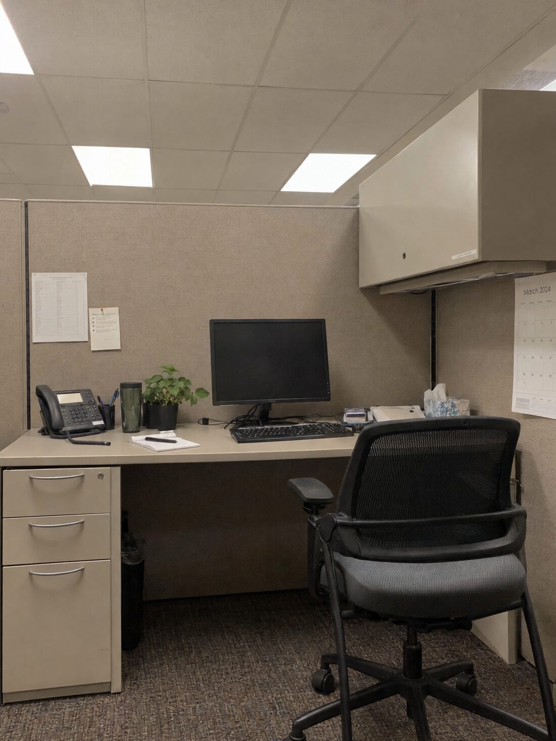 A beige office cubicle under fluorescent lights.